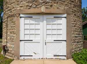 Door, Water tower, Ellwood House, DeKalb, Illinois. "On the west (rear) of the Ellwood House, the circular limestone water tower is about 50 feet (15.2 m) tall and has a diameter of 18 feet (5.5 m). The tower has windows occurring at different
