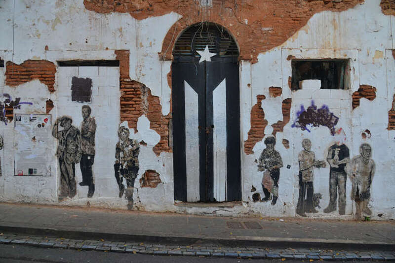 This door used to be painted like a full color Puerto Rican flag.  However, it is now painted as a black and white version of the flag.  The front of the building also has cut-out pictures of people on it.