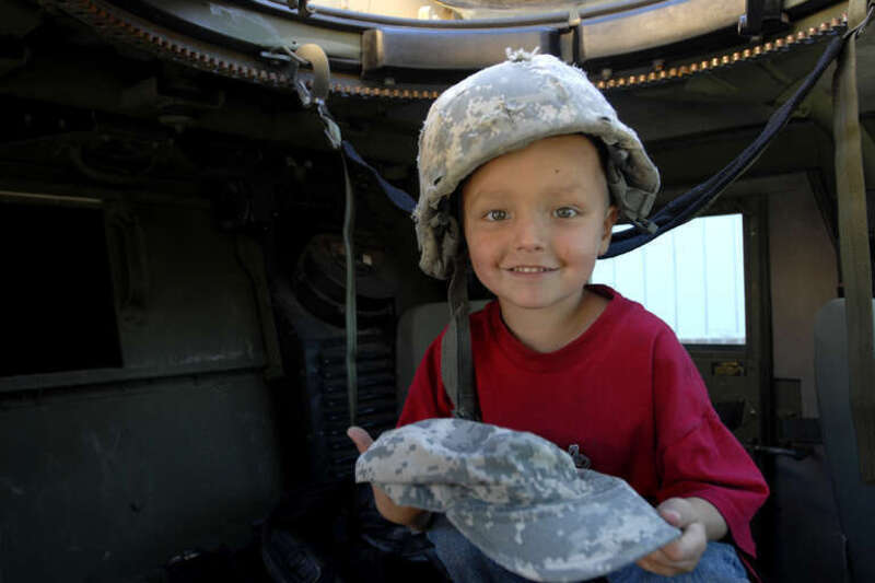 Four-year-old Syxx Bullplume of Tacoma, Wash. sits inside a humvee with a helmet on his head and a patrol cap in hand, Sept. 25, at the Lakewood Towne Center during &quot;Lakewood Salutes.&quot; Soldiers with 4th Stryker Brigade Combat Team, 2nd Infantry