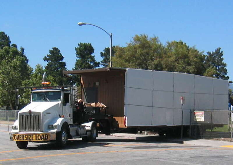 half portable modular classroom on truck leaving school grounds wide load