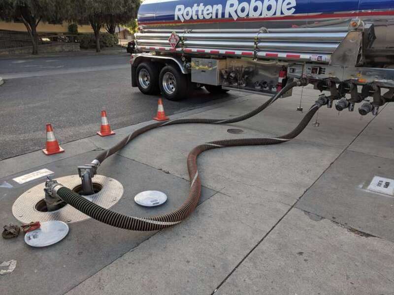 A tanker truck uses hoses to refill underground tanks with fuel at a Rotten Robbie gas station in Campbell, California.