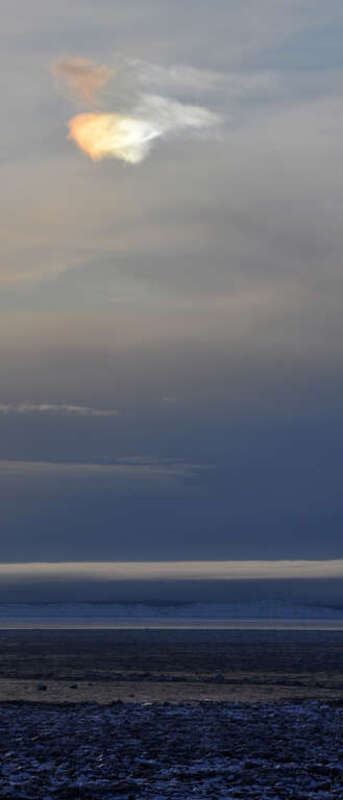 An iridescent cloud hovers above the icebergs in Cook Inlet. This might be an atmospheric phenomenon called a  "sundog," but I'm not totally sure.

winterbear.com