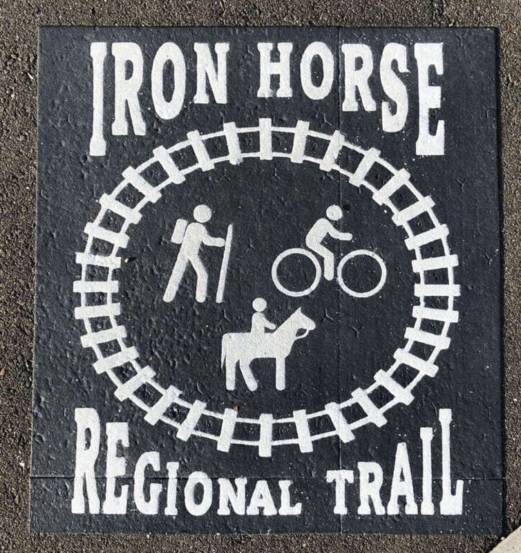 Trail signs placed on the street surface at intersections between the Iron Horse Regional Trail and roads in Pleasanton, California