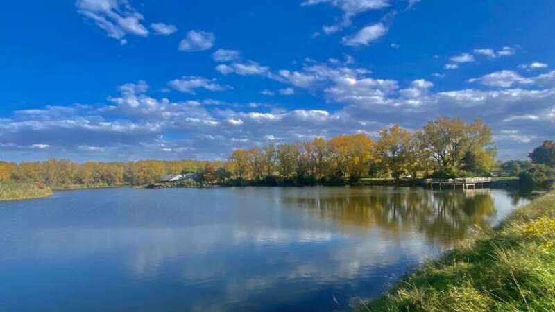 The autumn foliage in its full splendor makes a colorful backdrop for a view across Lake Kirsty, at the Tifft Nature Preserve in Buffalo, New York, as seen on an October 2022 afternoon.