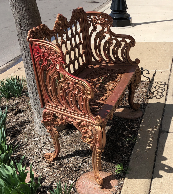A metal bench located on the northwest corner of the intersection of Chicago and Harlem, in Oak Park, Illinois