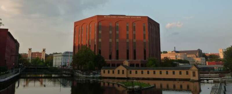 The main campus building of Middlesex Community College, located at 33 Kearney Square, Lowell, Massachusetts.  One of the Boott Mills is visible at left in the distance; part of the F. Bradford Morse Federal Building is also visible at left. The