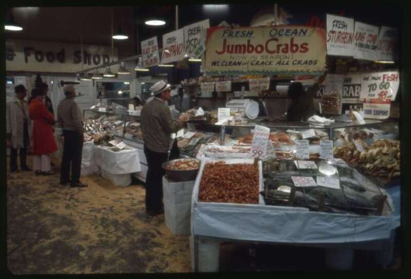 Shopping for seafood at Pure Food Fish in the Pike Place Market, Seattle, Washington, 1975. This is in the Main Arcade a few years before it had a major rehabilitation.