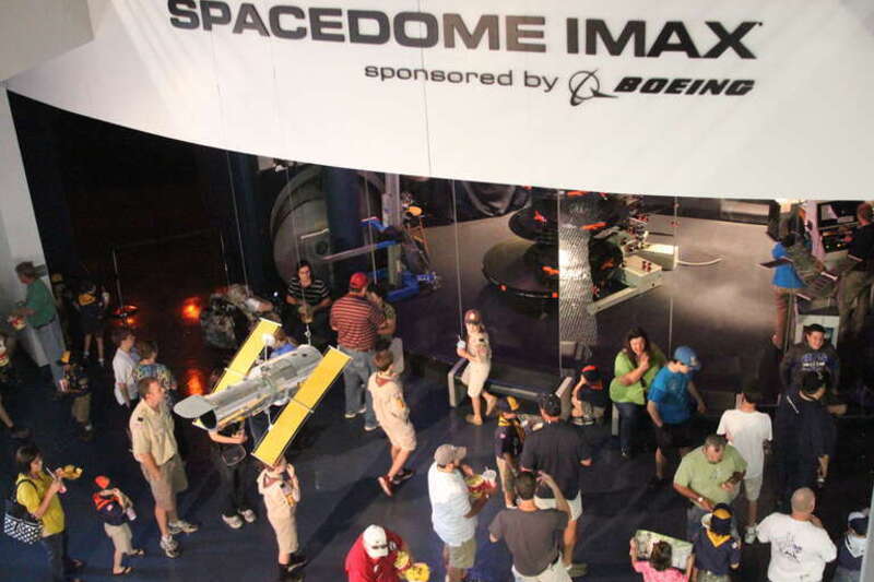 Patrons await entry to the IMAX theater at the United States Space &amp; Rocket Center.  A model of Hubble Space Telescope is suspended in the foreground.