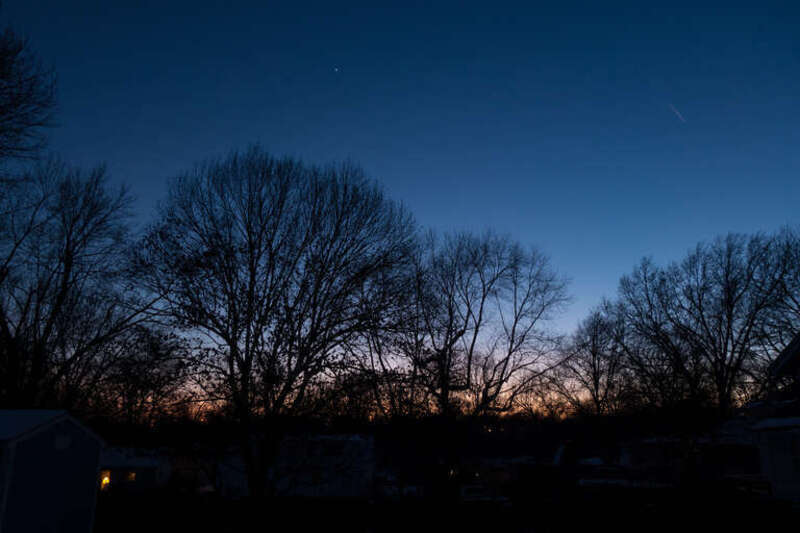 500px provided description: Winter sunset evening glow. Blue sky with Venus and possible meteor [#sunset ,#winter ,#twilight ,#evening ,#kansas ,#contrail ,#neighborhood ,#meteor ,#venus ,#bare trees ,#cloudless sky ,#horizion]
