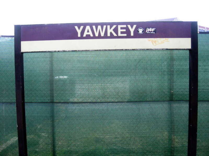 Station sign at Yawkey, complete with graffiti, set against the sheeting of the reconstruction project