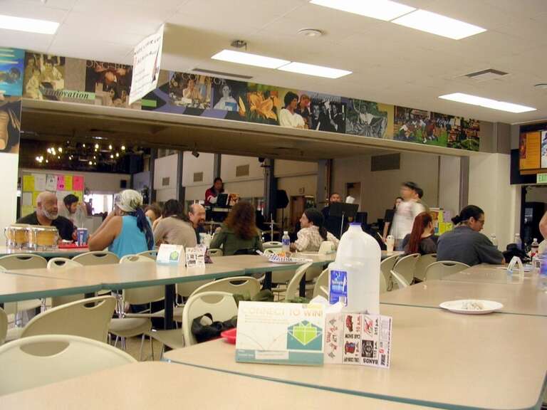 A light crowd sitting at the Long Beach City College (Liberal Arts Campus) cafeteria while a live jazz band performs on stage.The photograph was taken with a Nikon Coolpix e3200 digital camera and edited (for brightness, contrast, color balance and