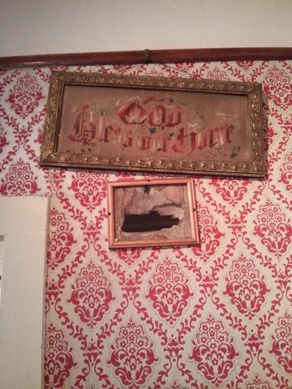 Hole in the wall originally from the shot that killed Jesse James. Later tourists damaged the wall further by taking souvenirs.