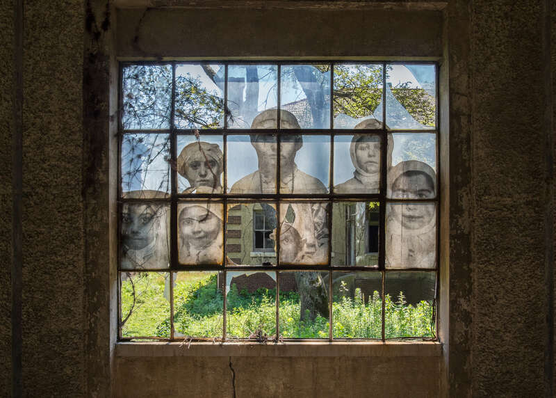 A window in the Ellis Island Immigrant Hospital, closed since 1930. The photograph is one from the early 20th century, when the hospital was operational. In 2014 the French artist JR put up large reproductions of such photographs around the hospital