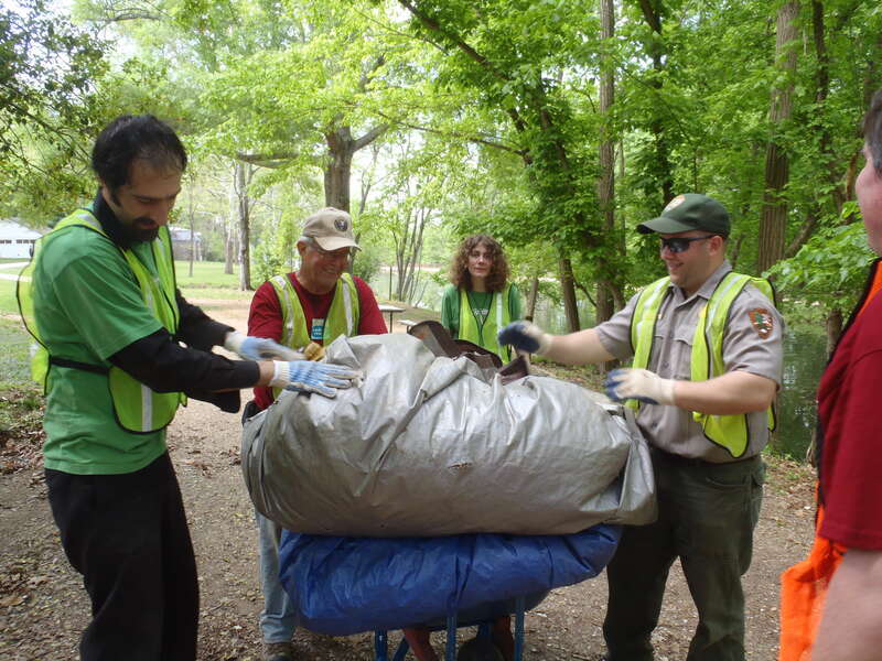 Volunteers and staff rake leaves around the parking lot and day use area