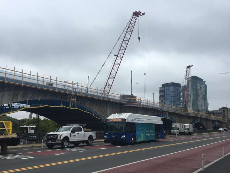 An EZRide bus on Charles River Dam Road, with Lechmere Viaduct rehabilitation behind, in September 2020