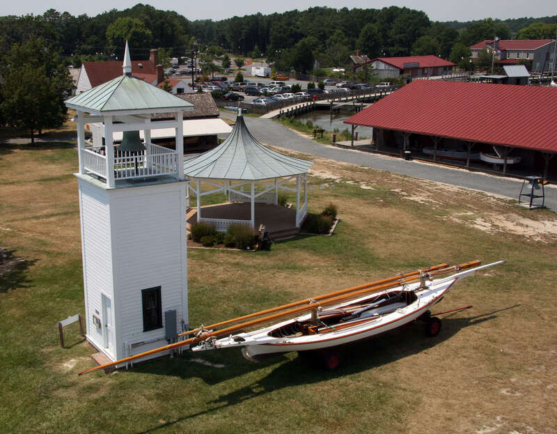 The log canoe Edmee S in front of the Point Lookout bell tower at the Chesapeake Bay Maritime Museum, Saint Michaels, Maryland, USA