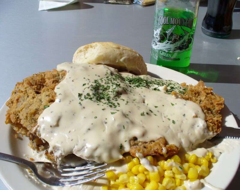 Chicken fried steak covered with gravy, corn (maize), a bread roll, and bottle of soda pop as served by Pops at 660 West Highway 66 in Arcadia, Oklahoma, USA.