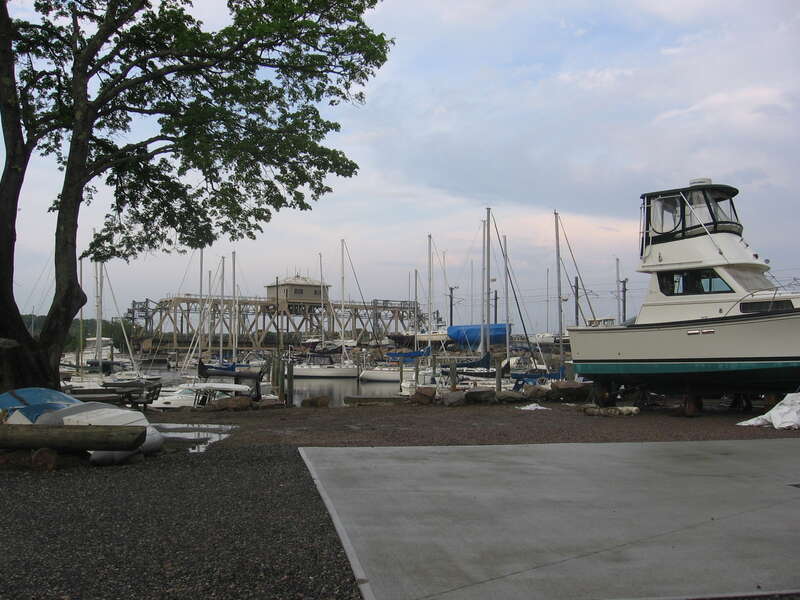 The swing bridge at the mouth of the Mystic River in Mystic, Connecticut is swung open to allow passage of boat traffic.  This view is looking east from the western or right bank of the river.