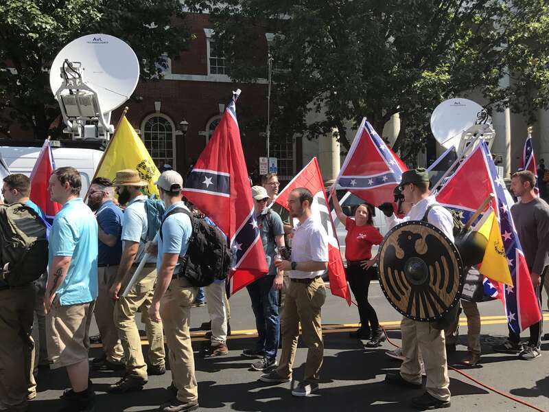 Alt-right members preparing to enter Emancipation Park holding Nazi, Confederate, and Gadsden &quot;Don't Tread on Me&quot; flags.