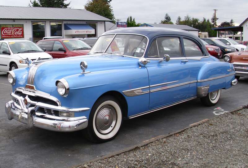 1952 Pontiac Chieftain 2-door sedan on a used car lot, asking $13,995. Nice looking car. I wonder if what is under the hood is original?