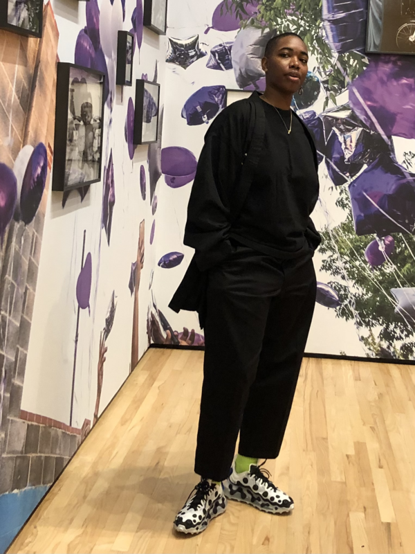 Image description: SHAN Wallace at the Baltimore Museum of Art in her exhibition &quot;SHAN Wallace: 410&quot;. She is wearing all black with her hands in her pockets.
