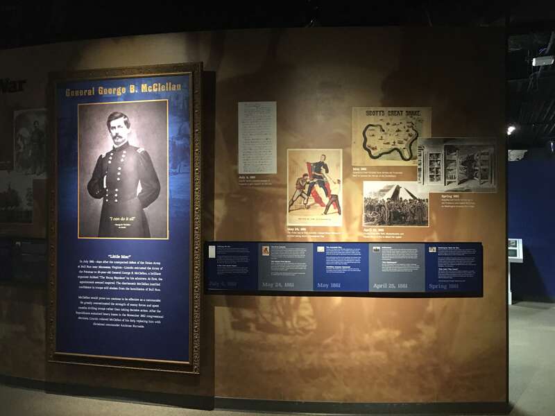 A wall at a museum exhibit with seven text panels and five images.
