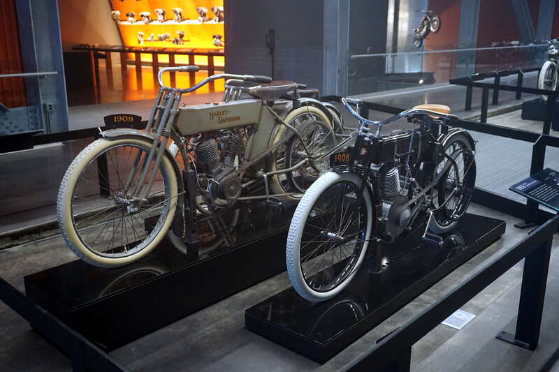 A 1909 Harley-Davidson Model 5-D (with an Atmospheric-Valve V-Twin engine) and a 1906 Harley-Davidson Model 2 (with an Atmospheric-Valve Single engine) at the Harley-Davidson Museum in Milwaukee, Wisconsin (United States).