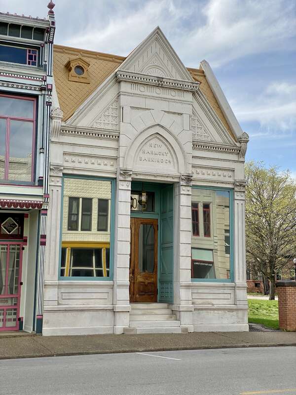 Built in 1882, this Gothic Revival-style building was constructed to house the New Harmony Banking Company.  The building features a limestone facade with a mansard and front gable roof, decorative carved stonework, cornices with dentils, decorative