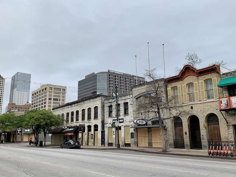 Windows on 6th Street in Austin, Texas are boarded up after bars were ordered closed during the 2020 Coronavirus pandemic.