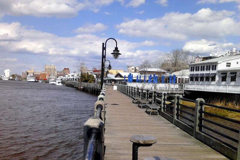 The Wilmington Riverwalk in North Carolina along the Cape Fear River with downtown Wilmington in the background.