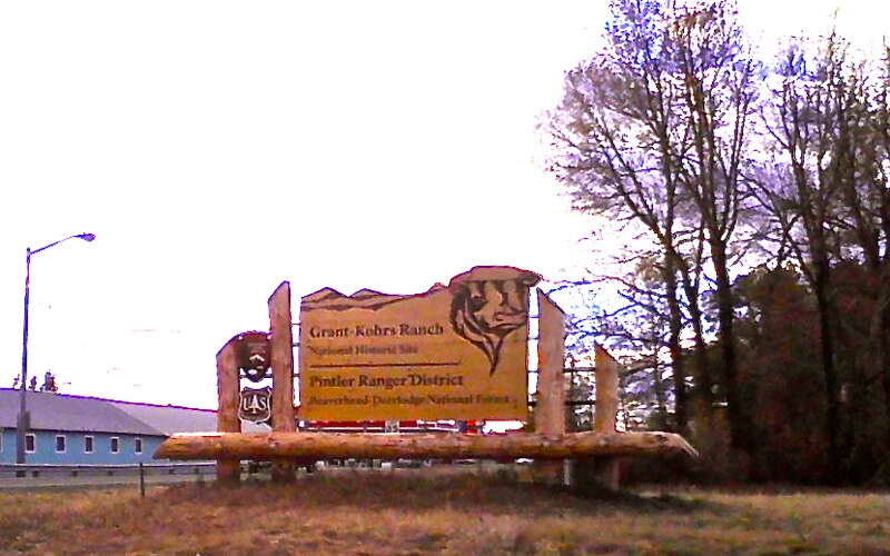Entrance sign, Grant-Kohrs Ranch.  Blue building visible in background is part of Powell County fairgrounds