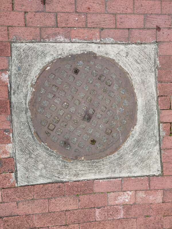 Sewer cover on brick sidewalk
