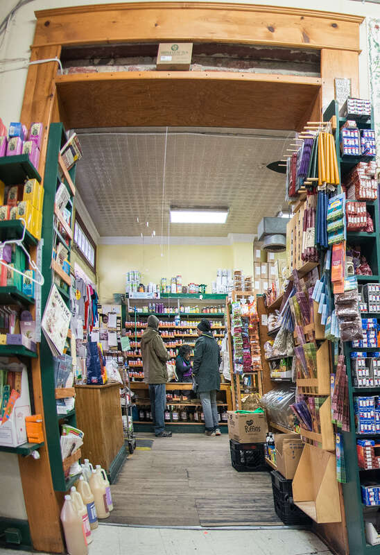 Glut collective member Shauntrice Martin  working the main register, welcomes and helps customers along with fellow worker-owners and volunteers, and take care of accounts payable to vendors at this worker-owner cooperative store, that serves the