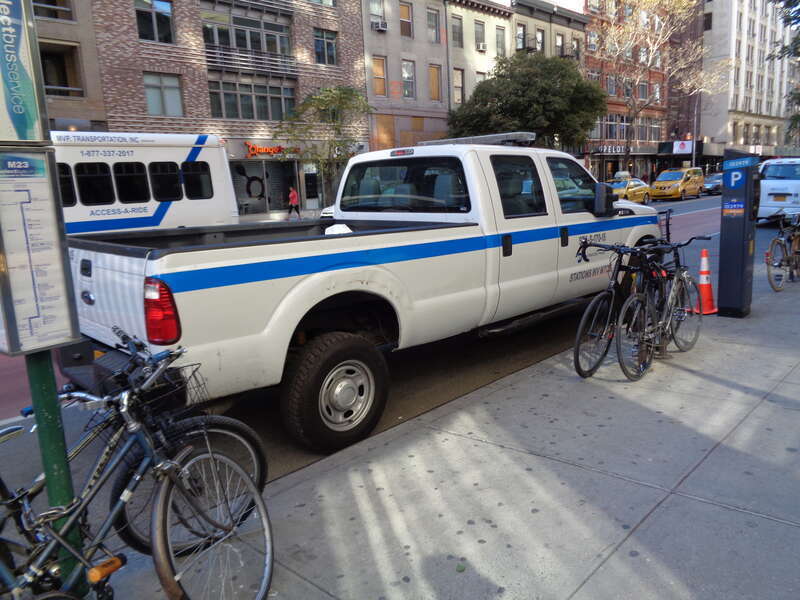 A NYCT pickup truck at the stop for westbound (Chelsea-bound) M23 SBS buses at 23rd Street between 6th Avenue and 7th Avenue in Chelsea, Manhattan. The stop is listed as West 23rd Street and 6th Avenue.