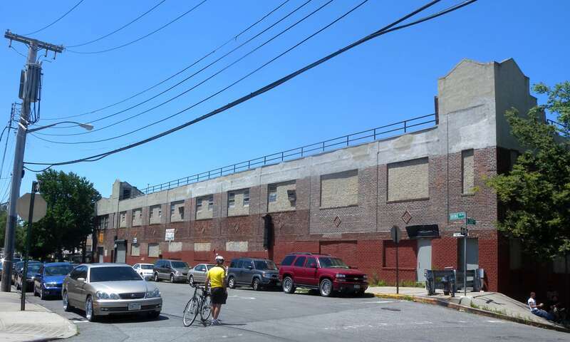 Looking west across 242nd Street and Bronx Boulevard as Joseph awaits his Drop duty on a sunny morning in front of a closed factory building.