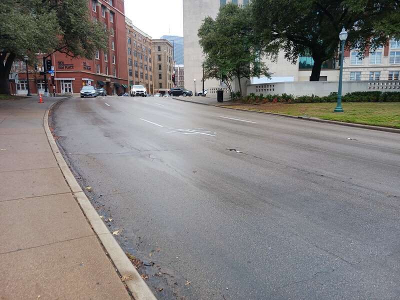 Here we see the X's on the Elm St. Dallas TX USA pavement marking the Kennedy assassination very clearly. This is the northeast twin X. 
 We are looking east at it.