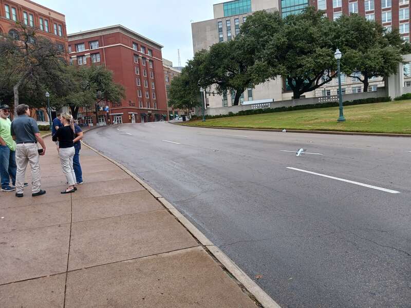 Elm St. in Dallas TX. Here we see the X's on the pavement marking the Kennedy assassination very clearly. This is the southwest single X. In the background we see the window of the former Texas School Book Depository.
