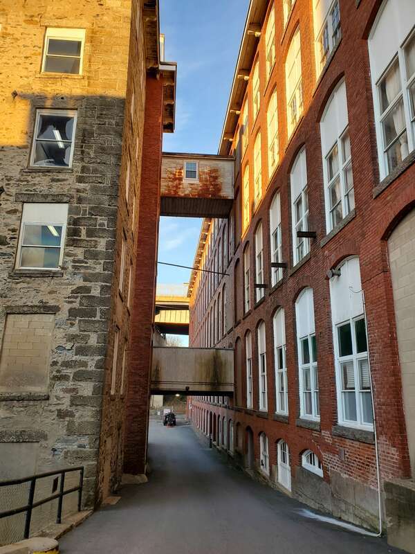 Driveway between the American Printing Company (right) and Metacomet Mill, seen in December 2021