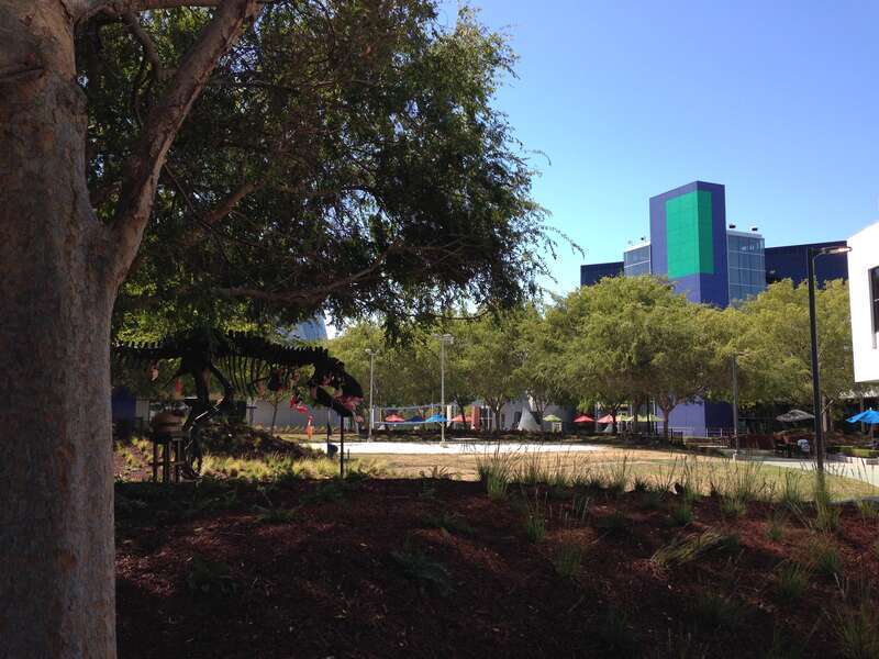 A T-Rex skeleton is in the shadows, with pink flamingoes all over it.