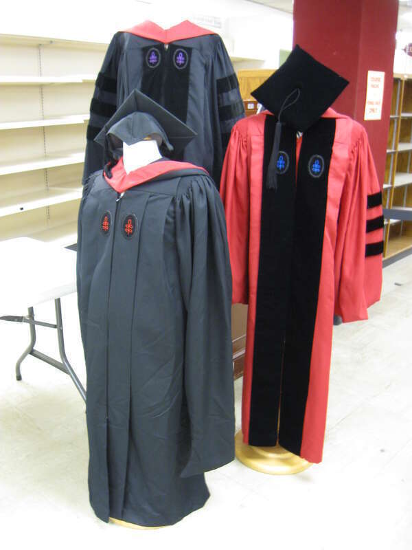 A display of the academic regalia of Harvard University.  Top left: Harvard Law School professional doctorate; bottom left: Harvard Divinity School masters degree; right: Graduate School of Arts and Sciences Ph.D. degree