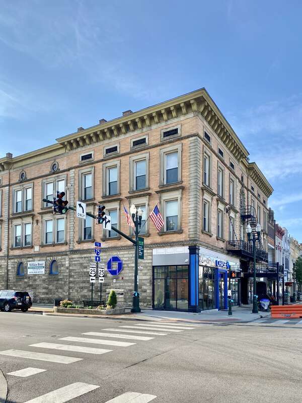 Built in 1896, this Beaux Arts-style former hotel stands at the corner of Main Street and Wooster Street in Bowling Green, Ohio.  The building features an orange roman brick facade, limestone trim, decorative window surrounds, oxeye windows, roman