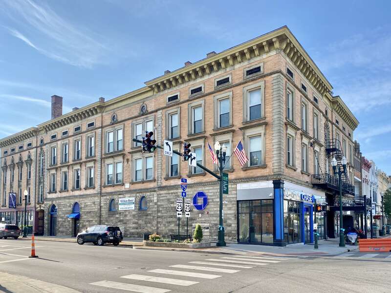 Built in 1896, this Beaux Arts-style former hotel stands at the corner of Main Street and Wooster Street in Bowling Green, Ohio.  The building features an orange roman brick facade, limestone trim, decorative window surrounds, oxeye windows, roman