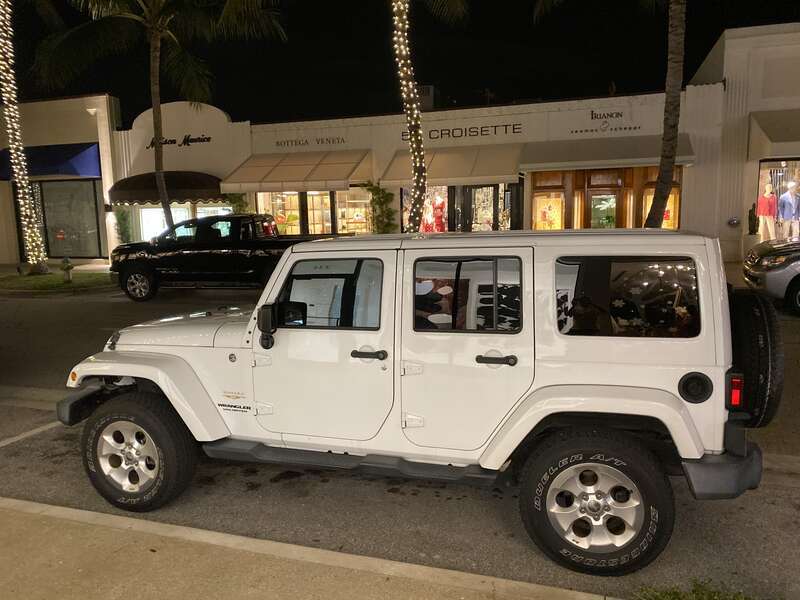 Jeep Wrangler Unlimited Sahara (JK) four-door finished in white. Photographed while parked on Worth Avenue in Palm Beach, Florida