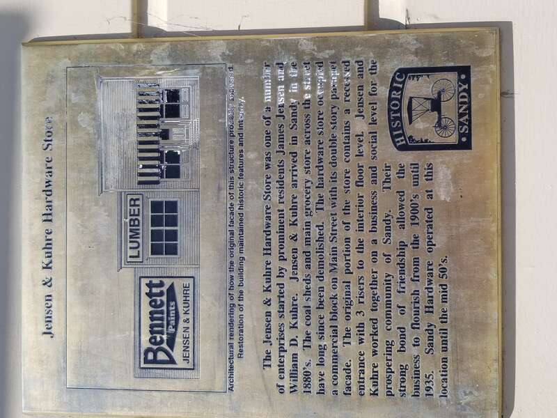 This is a placard mounted on the side of the building by the historical society of Historic Sandy providing information on what the building once was in the early 1900's