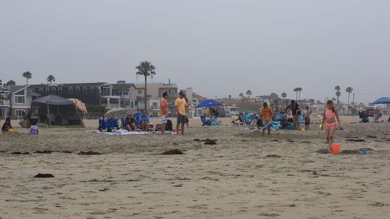 Spectators and supporters hang out on the beach on this cool, overcast morning as they wait for the swimmers to arrive.
The 2019 Newport Pier to Pier Two-Mile Swim was held Saturday, July 13, 2019 and facilitated by Newport Beach Lifeguard