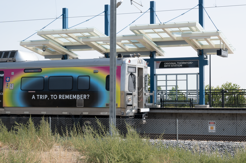 Original Thornton &amp;amp; 88th RTD station viewed from west. In foreground a southbound RTD commuter rail train has stopped to collect passengers.