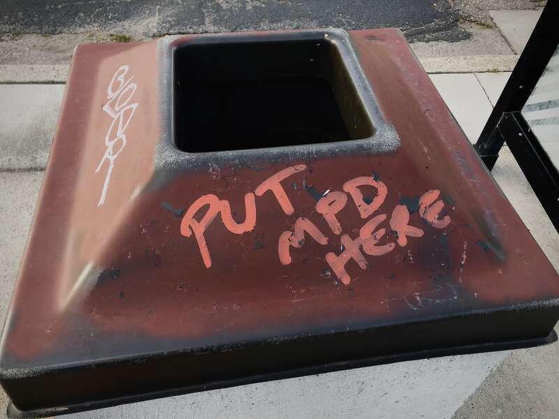 Vandalized trash can that reads "Put  here", found near George Floyd Square