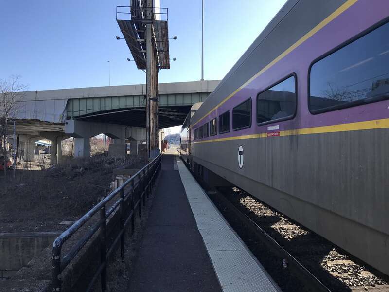 The low-level portion of the single side platform at Worcester Union Station, seen in April 2021 with an MBTA Commuter Rail train laying over. The Interstate 290 Viaduct is visible in the background