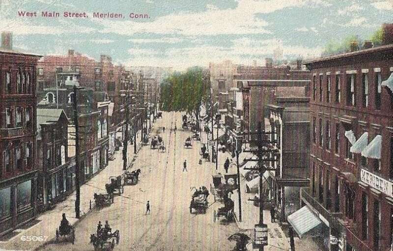 Bird's-eye view postcard of West Main Street in Meriden, Connecticut from a postcard mailed in 1912. All the vehicles on the street are horse-drawn. Trolley tracks can be seen down the middle of the street, which may not be paved.