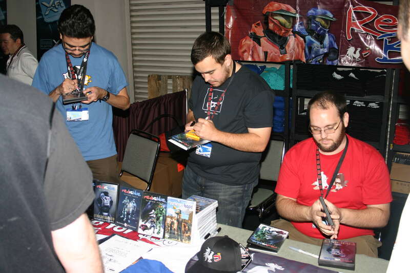Gus Sorola, Jason Saldaña, and Dan Godwin giving autographs at the Red vs. Blue merchandise booth at PAX 2006.